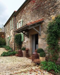 an old stone house with green shutters and potted plants