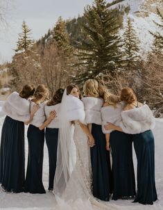 a bride and her bridesmaids in the snow with their fur stoles on