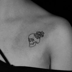 a black and white photo of a skull with flowers on its chest