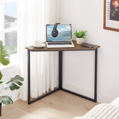 a laptop computer sitting on top of a wooden desk next to a potted plant