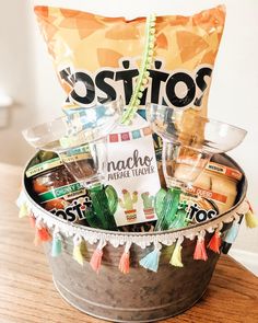 a bucket filled with lots of tacos and other items on top of a wooden table