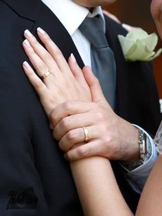 a close up of two people wearing wedding rings and holding each other's hands