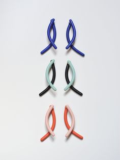 four different colored hair clips sitting next to each other on a white surface in the shape of an x