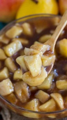 a wooden spoon filled with apples and caramel sauce on top of an apple pie