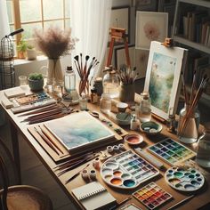 an artist's desk with art supplies and paintings on it, including watercolors