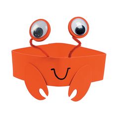 an orange box with googly eyes and two hands holding it in the shape of a crab