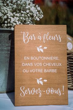 a wooden sign that says bar a fleurs on the table next to a potted plant