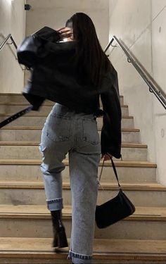 a woman is walking up some stairs with her hand in her pocket and holding a purse