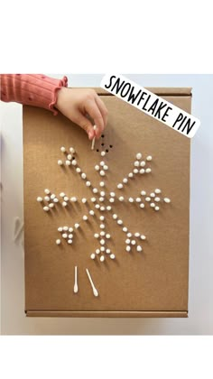 someone is making a snowflake out of white balls