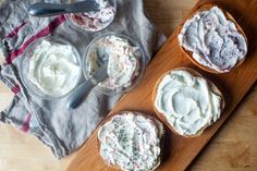 three cupcakes on a cutting board with frosting in them and two spoons