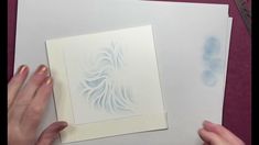 two hands are working on an intricate paper art project with blue and white inks