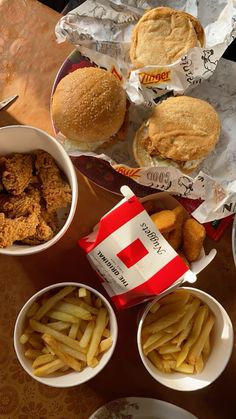 several different types of food are sitting on the table, including burgers and french fries