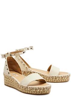 Info & Care:.Valentino Garavani grained leather espadrilles.Espadrille wedge heel measures 2 inches/ 50mm.Rockstud embellishments, whipstitch trims, metallic weave at wedge sole, rubber sole, round toe.Adjustable buckle-fastening ankle strap.Size & Fit:.Displayable Product Name: Rockstud 50 leather wedge espadrilles.Style Number: 956982.Merret Style Number: 956982.Department Description: WOMENS SHOES.Department Number: 140.Visible In Search: true.Season: RA23.Supplier Brand: VALENTINOG.Family Of Business: 006.Runs To Size: This style runs true to size.Restricted Delivery UK: false.Restricted Delivery Europe Exc Ireland: false.Restricted Delivery Ireland: false.Restricted Delivery America: false.Restricted Delivery Asia Exc Hong Kong: false.Restricted Delivery Hong Kong: true.Restricted Del Summer Wedge Sandals With Studded Rubber Outsoles, Summer Wedge Sandals With Studded Outsoles, Flat Heel Espadrilles With Branded Heel Counter For Summer, Valentino Espadrilles, Valentino Garavani Shoes, Espadrilles Style, Wedges Shoes, Wedge Espadrilles, Leather Espadrilles