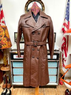 "Top quality Vintage men's trenchcoat from the fabulous 1970s. No makers label although it could possibly be  Hepworths for Hardy Amies. Nice conker brown colour,thick leather,fab wide highwaymans colour measuring near 6\"inches,front panel consisting of 8 buttons,epaulets in the shoulders and cuffs are just for show and do not unbutton,fab rear vent is an impressive 16&1/2\" inches and overall apart from the left side this coat is in great condition,looks like the fella who owned this had a fall as it looks like a graze down the side like it's fallen on a path or road etc,not heavily noticeable but it is there,couple of light marks to shoulders,arms,back etc but all light. Marked as a 42\" chest but please NOTE    this is a medium to 41\"chest max now,vintage clothes do seem to shrink ove Retro Brown Double-breasted Outerwear, Vintage Brown Long Coat, Vintage Double-breasted Outerwear, Retro Brown Outerwear For Vintage Fashion, Vintage Fitted Belted Outerwear, Fitted Vintage Belted Outerwear, Hardy Amies, Northern Soul, Brown Colour