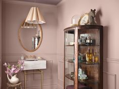 a bathroom with pink walls and gold trim on the wall, including a corner cabinet