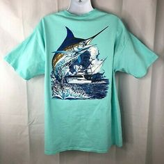 a blue t - shirt with a sail boat on it and the image of a marlin