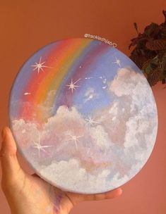 a hand holding up a painted plate with a rainbow on the side and stars in the sky