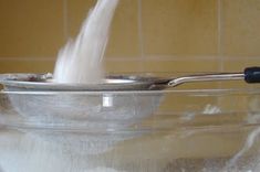 a spoon is pouring milk into a glass bowl