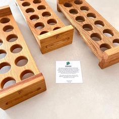 three pieces of wood with holes in them on a table next to a business card