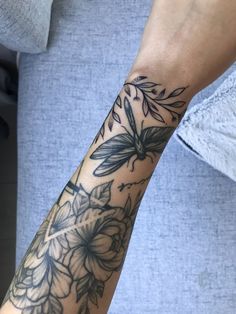 a woman's arm with flowers and leaves tattooed on the side of her arm