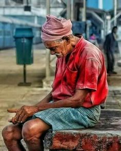 an old man sitting on top of a brick bench