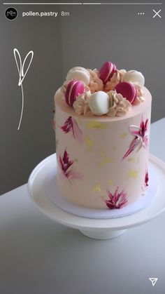 a pink cake decorated with candy and candies on a white platter in front of a gray wall