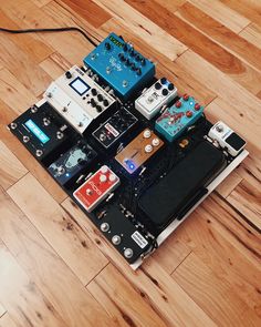 an assortment of pedals and amps sitting on top of a wooden floor