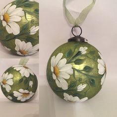 a green ornament with white flowers painted on the front and back, hanging from a ribbon