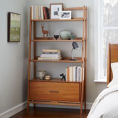 a bedroom with a bed, bookshelf and pictures on the wall