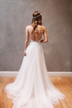 a woman in a white wedding dress standing on a wooden floor with her back to the camera