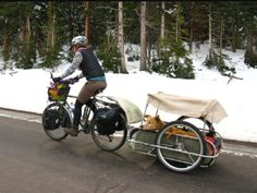 a person riding a bike with a dog in the back seat and a trailer attached to it