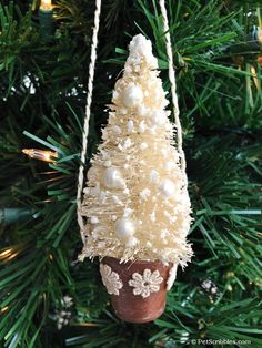 an ornament hanging from a christmas tree decorated with white beads and snowflakes