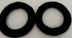 two pieces of black wool are placed in the shape of circles on a white surface