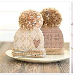 two knitted hats with hearts on them sitting on top of a white saucer