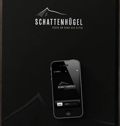 an iphone sitting on top of a black box with the logo schattenhugel