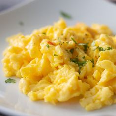 scrambled eggs on a white plate with parsley