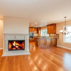 an empty living room with wood flooring and a fire place in the fireplace area