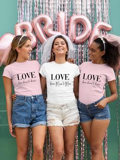 three girls wearing matching shirts and denim shorts standing in front of a backdrop with balloons