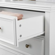 a white dresser with two drawers and a pink towel on the bottom drawer next to it