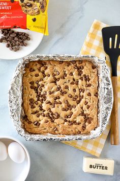 a baking pan filled with chocolate chip cookie dough next to an egg and other ingredients