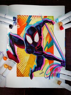 a spiderman drawing on a piece of paper next to crayons