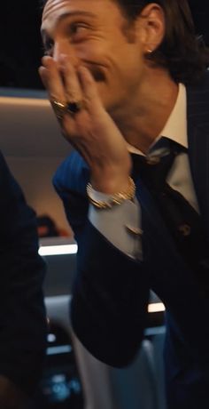 a man wearing a suit and tie holding his hands to his mouth