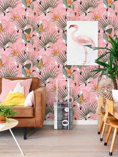 a living room filled with furniture and a pink wallpaper covered in flamingos, palm leaves