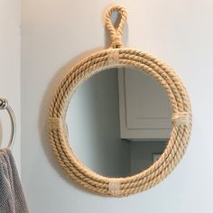 a rope mirror hanging on the wall next to a towel rack