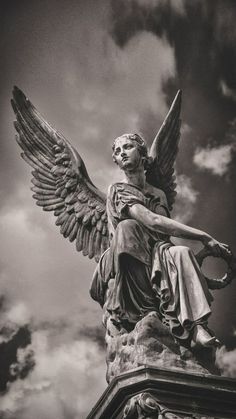 an angel statue sitting on top of a pillar