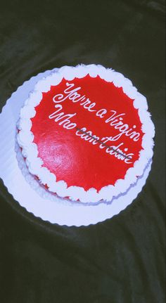 a red and white cake on top of a black table with words written on it