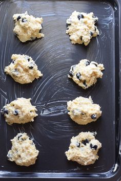 six cookies with blueberries are on a cookie sheet ready to go into the oven