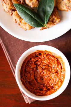 two plates filled with food on top of a wooden table next to a bowl of sauce