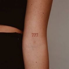 a woman's arm with a small tattoo that reads 777 on the side