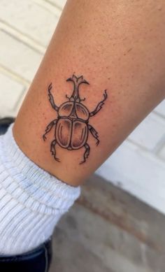 a ladybug tattoo on the left ankle is shown in black and grey ink